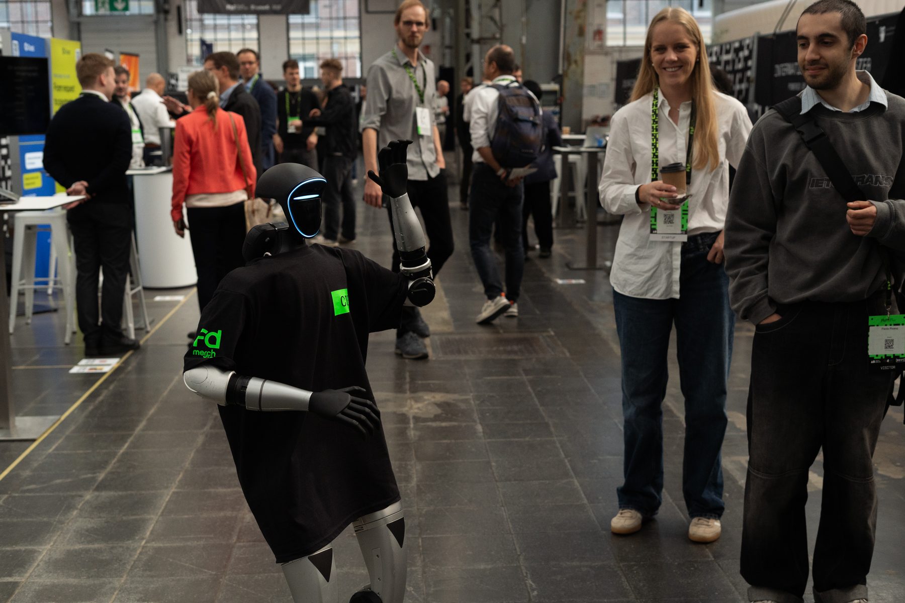 Roboter im T-Shirt tanzt vor Messebesuchern