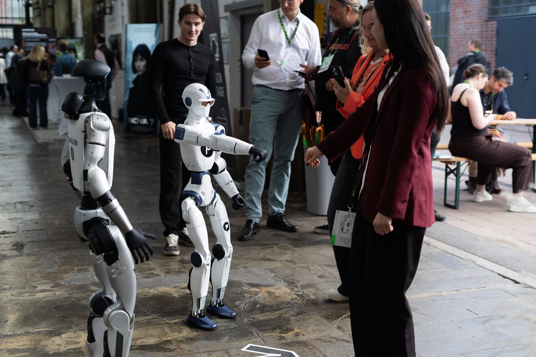 Zwei Roboter zwischen Besuchern in der Messehalle