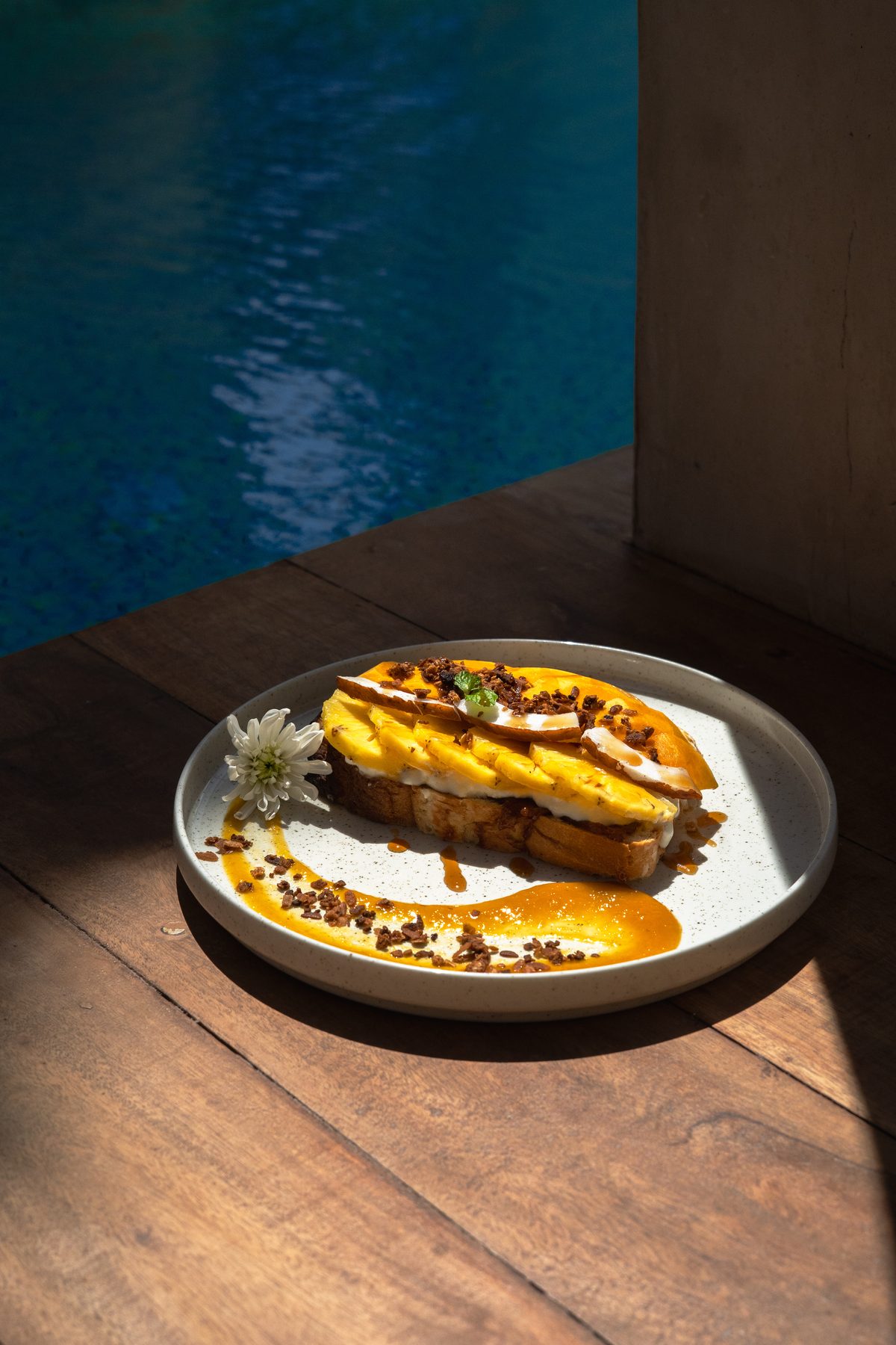 Toast mit Mango auf einem Holztisch am Pool